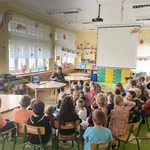 grupa dzieci siedząca na dywanie przed panią leśnik