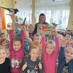 pani leśnik z grupąuśmiechniętych dzieci trzymających drewniane figurki ptaków pozują do zdjęcia
