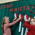 dwie dziewczynki wieszające biało-czerwone listki na gazetkę przedszkolną