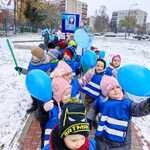 Dzieci idące w parach w niebieskich kamizelkach z balonami