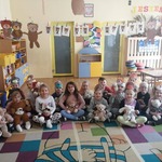 Grupa dzieci siedząca na dywanie z pluszowymi misiami 