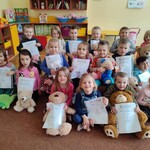 Grupa dzieci z pluszowymi misiami i kolorowymi dyplomami 