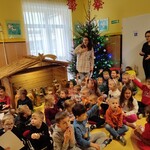Dzieci siedzące przy żłóbku i choince