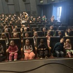 Dzieci siedzące na widowni w sali teatralnej 