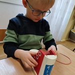 chłopiec bawiący się drewnianym butem do nauki sznurowania