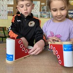 Dzieci bawią się drewnianym butem do nauki sznurowania 