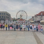 Grupa dzieci stojąca na Rynku Kościuszki w Białymstoku 