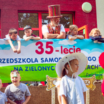 Prowadzacy i dzieci na tarasie nad banerem z napisem 35-lecie przedszkola.jpg