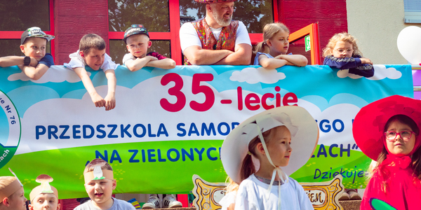 Prowadzacy i dzieci na tarasie nad banerem z napisem 35-lecie przedszkola.jpg
