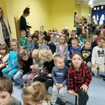 Dzieci z grupy Muchomorki i Biedronki siedzą na ławeczkach i śpiewają kolędy