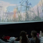 Grupa dzieci ogląda film w namiocie 