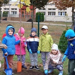 Grupa dzieci stoi przy posadzonym drzewku 