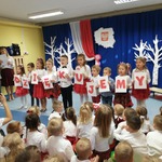Dzieci trzymające literki tworzące napis 