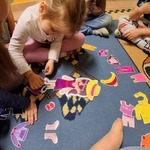 Dziewczynka układa puzzle na dywanie