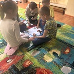 Dzieci siedzą w małej grupie na dywanie